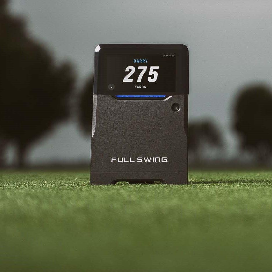 The Full Swing Golf KIT Launch Monitor by Full Swing Golf displays "Carry 275 Yards" on grass, with blurred trees behind, capturing a remarkable golf moment.