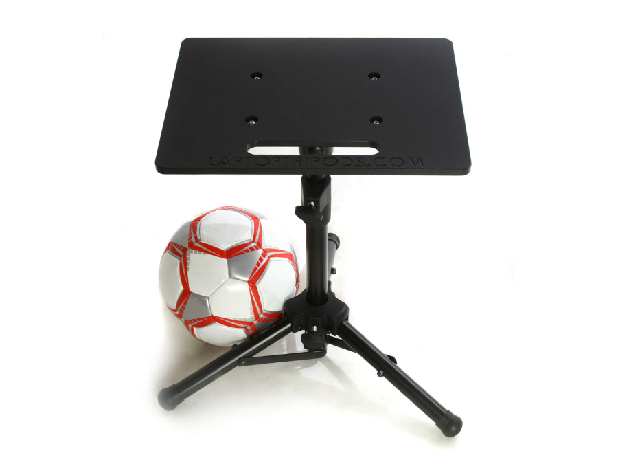An AllSportSystems Mini Portable Laptop Tripod Computer Stand in black is set up on a white surface next to a soccer ball.