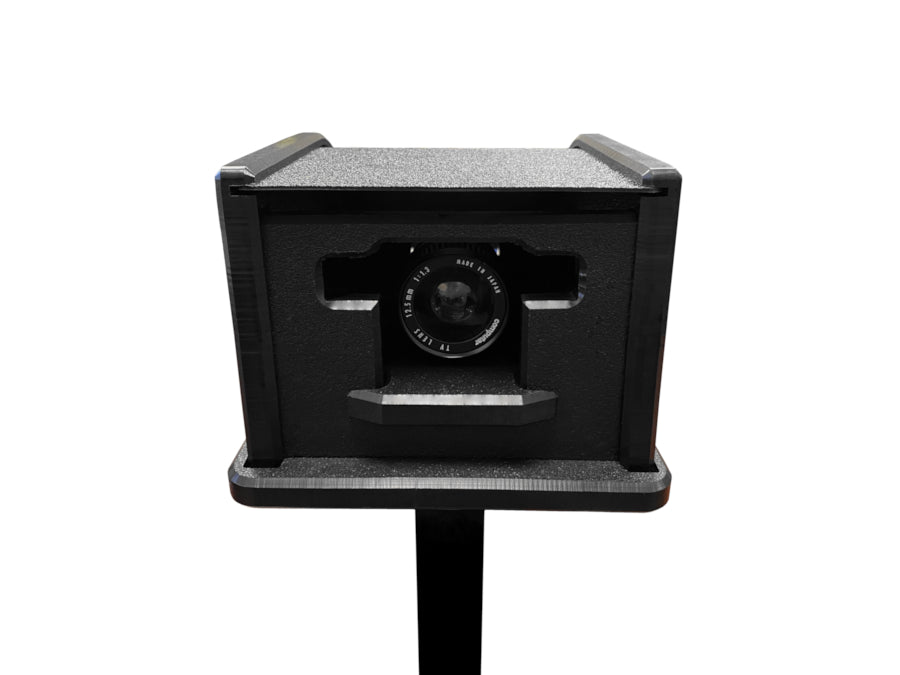 A black rectangular camera, encased in the AllSportSystems Rugged Video Camera Shield Enclosure, is mounted on a sturdy tripod stand with its lens perfectly centered against a plain white background.