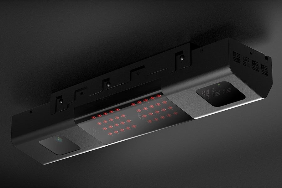 The Uneekor QED Golf Simulator Overhead Launch Monitor, a ceiling-mounted rectangular device featuring red LED lights, a small camera, and a red running figure icon in the bottom right corner, is a sleek creation by Uneekor designed to enhance precision in sports like golf.