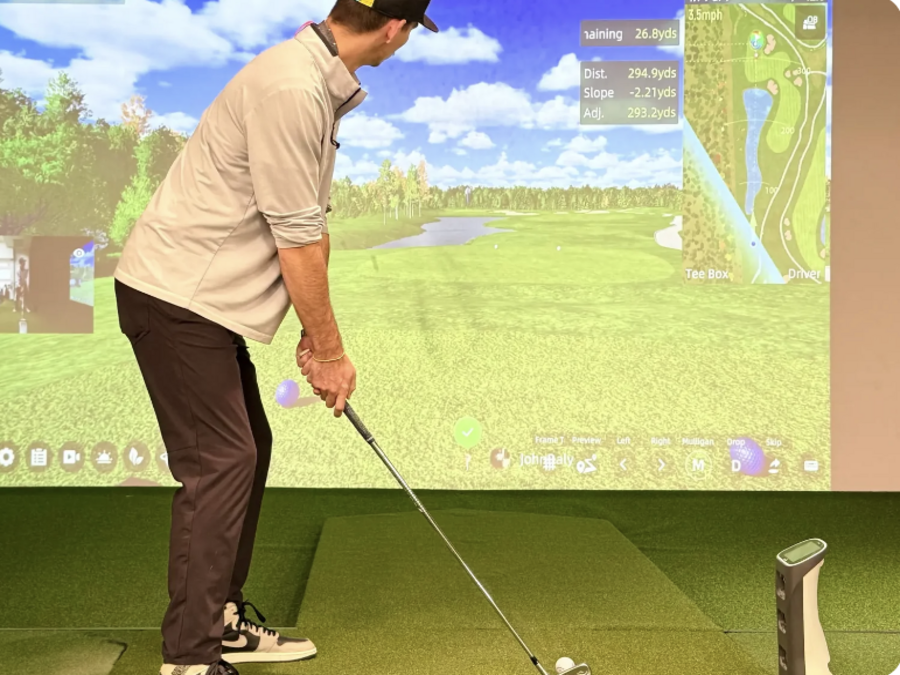The GOLFJOY Spica 3 portable launch monitor in an indoor home golf simulator setup.